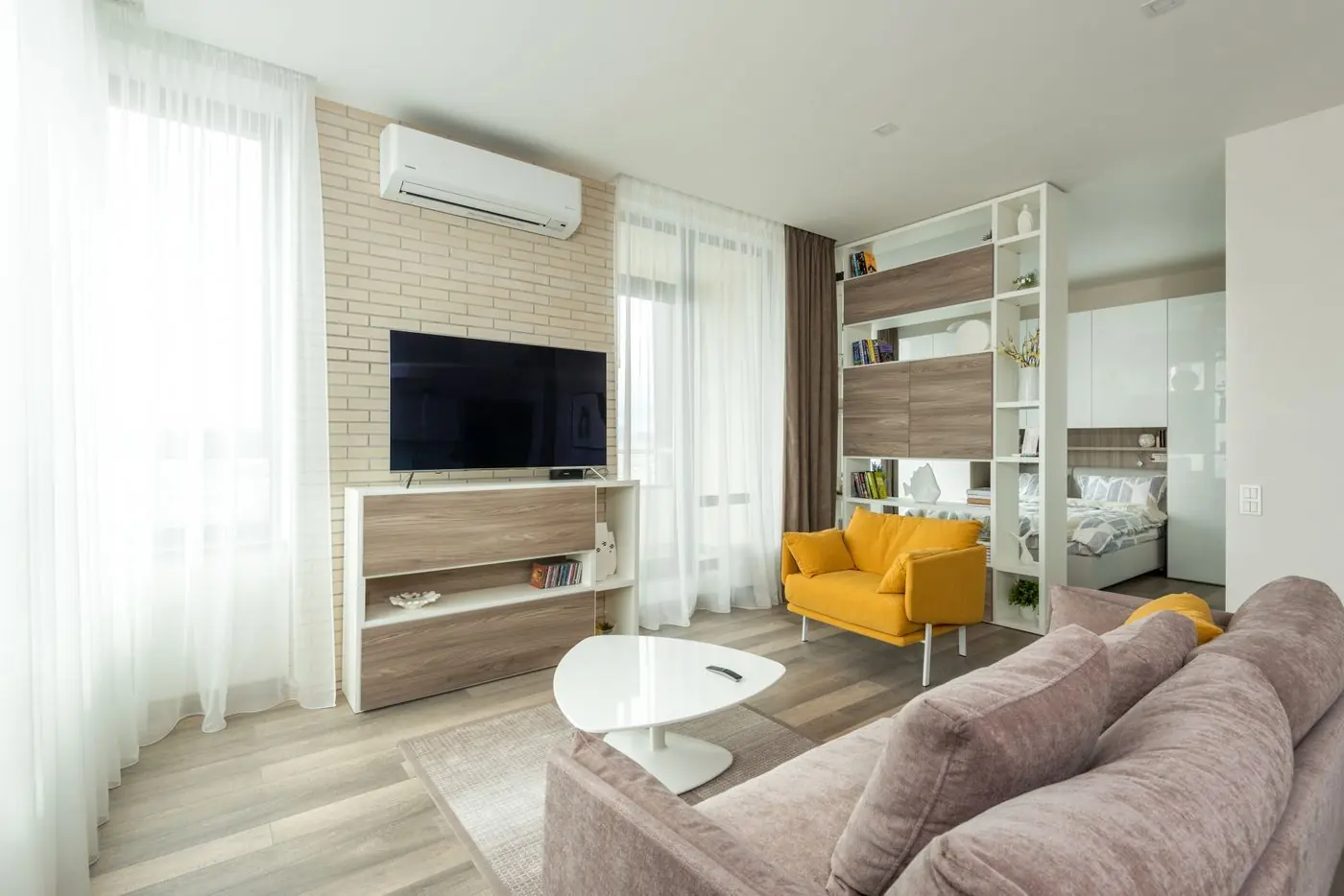Open woonkamer met gele fauteuil op een houten vloer
